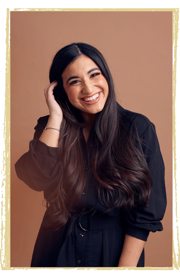 Rhea smiling with hand moving hair back